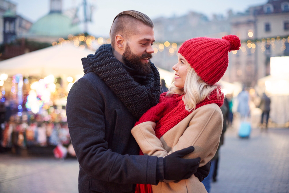 Couple s’enlaçant devant un marché de Noël lors d’un rendez-vous romantique à Strasbourg, rencontre organisée via l’application Jecontact